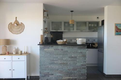 une cuisine avec une cheminée en briques et des placards blancs dans l'établissement Pietra Bella, à LʼÎle-Rousse