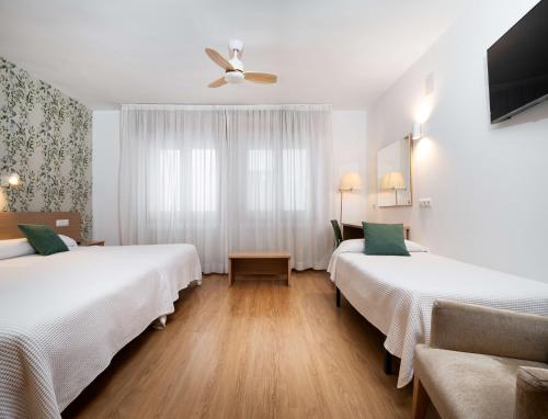 Habitación de hotel con 2 camas y ventilador de techo. en Hotel Mi Casa, en Sabiñánigo