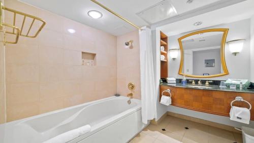 La salle de bains est pourvue d'une baignoire, d'un lavabo et d'un miroir. dans l'établissement Sleep 4 Stylish Boardwalk CozySuites Studio, à Atlantic City