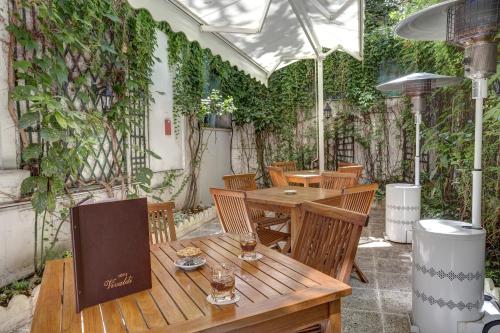 an outdoor patio with tables and chairs and vines at Hotel Vivaldi in Puteaux