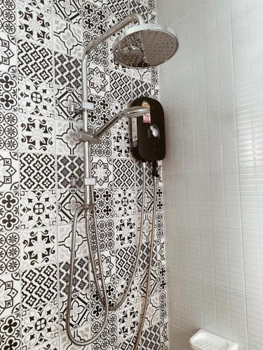 a shower in a bathroom with a black and white tiles at Hm House Patong in Patong Beach