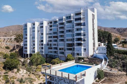 un immeuble d'appartements avec une piscine en face dans l'établissement Apartamento balcón del Mar, à Almería