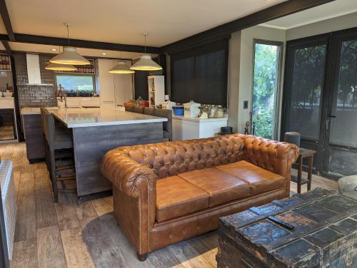 a living room with a leather couch and a kitchen at Citizen Kane Lodge - Hospedaje Gourmet in San Carlos de Bariloche