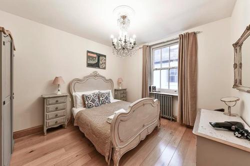1 dormitorio con cama y lámpara de araña en Knightsbridge 2BR Mews House, en Londres