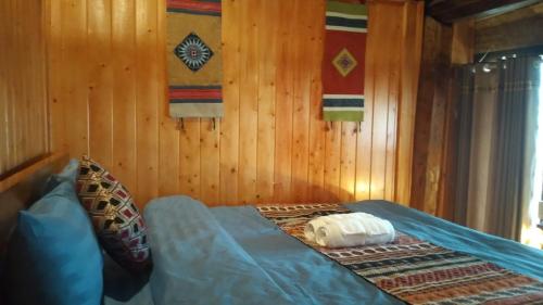 a bed in a room with wooden walls at Ta Xua Ecolodge in Bắc Yên
