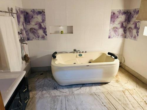 a white bath tub in a bathroom with a sink at Anand Nilaya (2.5 km from Sukhna Lake, Chd) in Chandīgarh