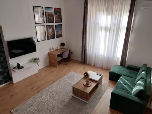 a living room with a green couch and a television at SQUARE 16 Apartman - Absolutely Central Location with Self Check In in Szombathely