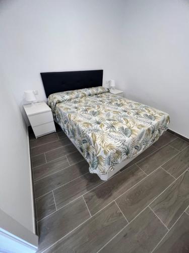 Apartamentos Montalvo Metrópolis A في توريمولينوس: سرير في غرفة مع أرضية خشبية