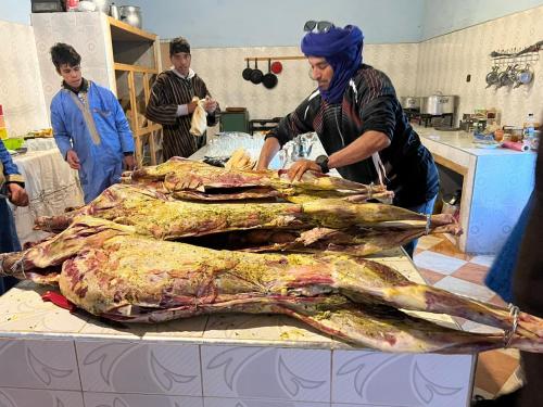 a group of people standing around a table with a large fish at Riad Ouzina TGM in Ouzina