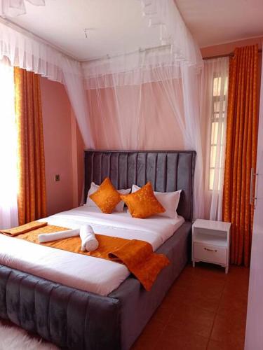 1 dormitorio con 1 cama grande con almohadas de color naranja en JABALI's Homestay, en Kisumu