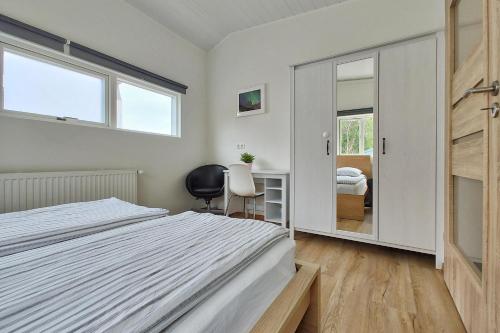 1 dormitorio con cama, escritorio y espejo en Túngata apartment, en Seyðisfjörður