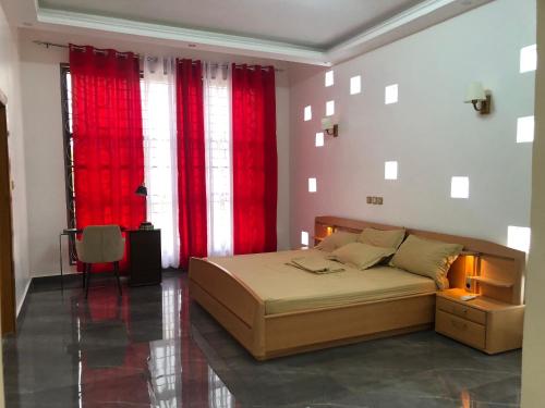 1 dormitorio con 1 cama grande y cortinas rojas en Maison d'architecte moderne, en Abomey-Calavi