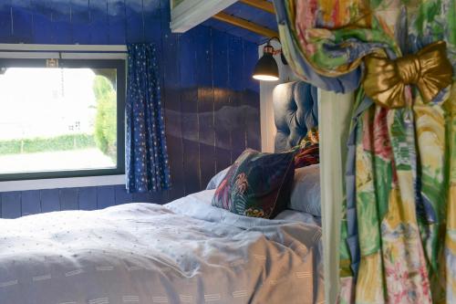 a bedroom with a bed with blue walls and a window at Colly Farm in Bridport