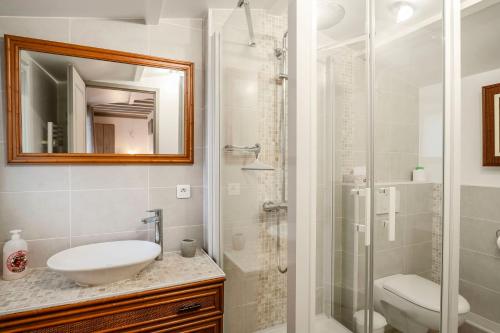 uma casa de banho branca com um lavatório e um chuveiro em La Bayardine em Sarlat-la-Canéda