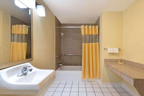 a bathroom with a sink and a tub and a shower at Days Inn by Wyndham Near Seaworld San Antonio in San Antonio