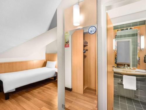 um pequeno quarto com uma cama e um lavatório em Ibis Budapest Heroes Square em Budapeste