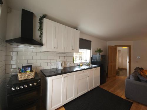 a kitchen with white cabinets and a black stove at Holiday in The Heart of Kerry in Castlemaine