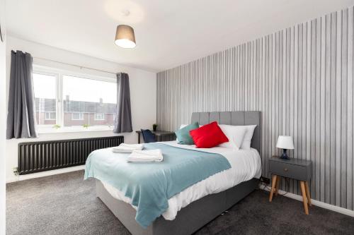 a bedroom with a large bed with red and green pillows at Worthy Rest in Stockton-on-Tees