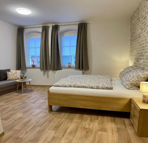 ANNA Gästehaus Zimmer في Pfreimd: غرفة نوم بسرير واريكة ونوافذ