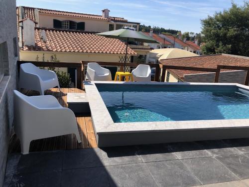 a swimming pool with white chairs on a roof at Sintra Breeze - Sun, Pool & Kitchen in Mem Martins