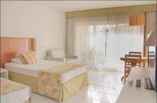 um quarto de hotel com duas camas e uma mesa em Búzios Beach Resort RJ em Búzios