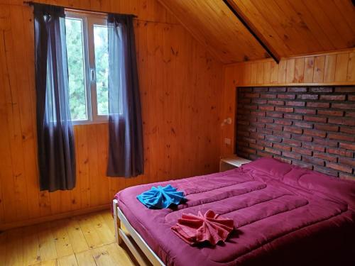 a large bed in a room with a brick wall at La Estrella complejo del lago in Villa Meliquina