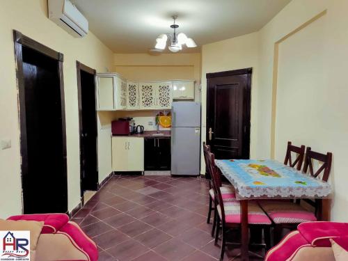 Porto Matroh New Chalets في مرسى مطروح: مطبخ مع طاولة وكراسي وثلاجة