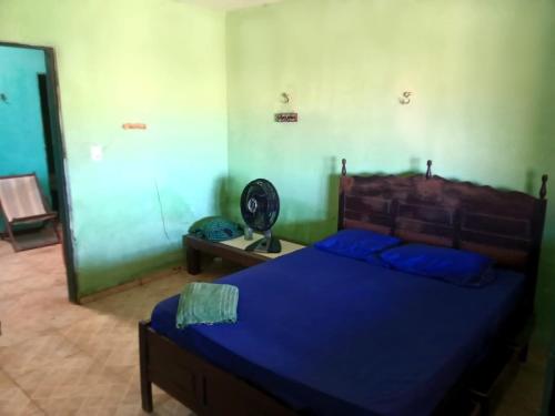 una camera da letto con un letto con lenzuola blu e un ventilatore di Aloha LC Hostel a Luis Correia