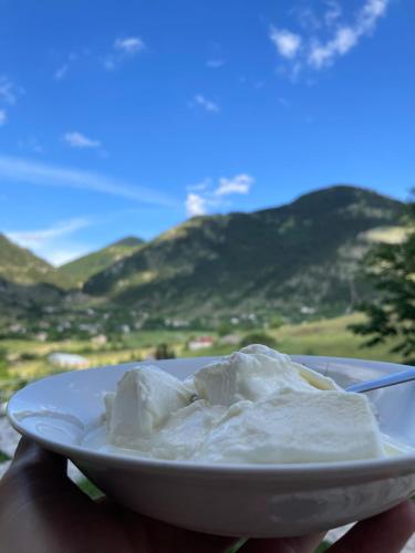 a person holding a plate with whipped cream on it at LURA Hotel in Peshkopi