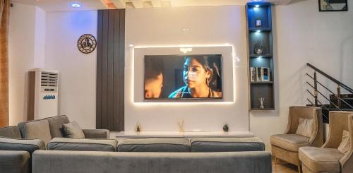 a living room with a couch and a tv on a wall at Urban Haven in Lekki