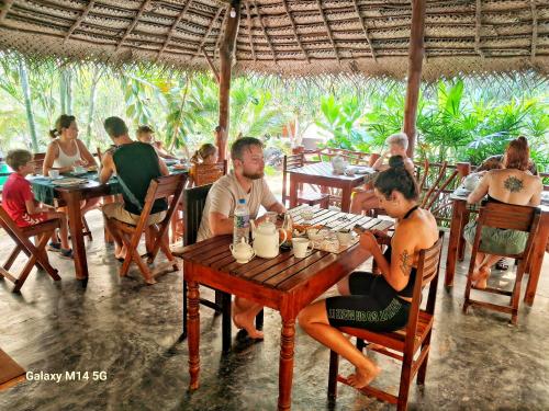 un grupo de personas sentadas en una mesa en un restaurante en Sea sound cabana & Restaurant, en Tangalle