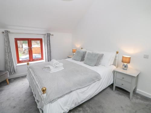 a white bedroom with a bed and a window at Croft Cottage in Castleton
