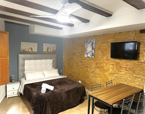 バレンシアにあるMurillo Apartmentのレンガの壁にテレビとベッドが備わるベッドルーム1室が備わります。