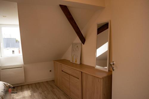 Schlafzimmer im Dachgeschoss mit einer Holzkommode und einem Spiegel in der Unterkunft Belles combles alsaciennes au centre de Strasbourg in Straßburg