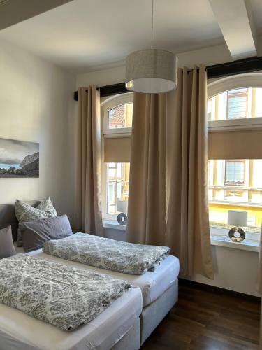 two beds in a room with two windows at Stangenberg`s City Loft in Hameln