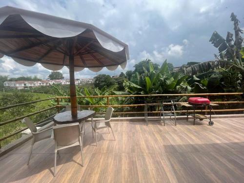 a patio with a table and chairs and an umbrella at Cabaña CAPRI Eje Cafetero in Circasia