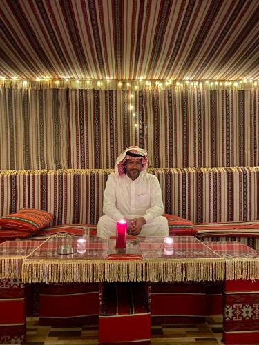 a man sitting at a table with a candle at Desert's Soul Wadi Rum in Disah