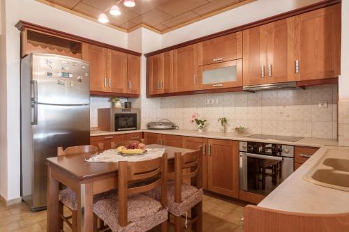 a kitchen with a table and a stainless steel refrigerator at sparrow apartment (Σπουργιτης) in Skoulikádhon