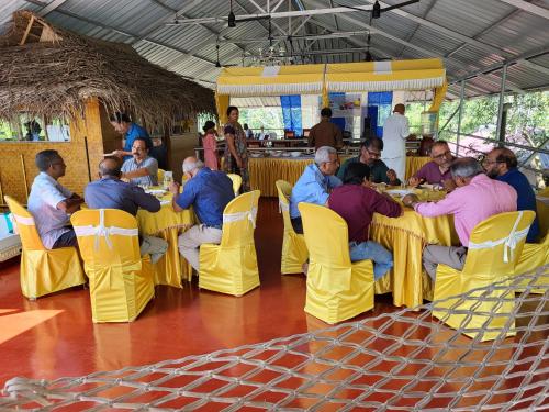 a group of people sitting at tables in a restaurant at Marari Beach Villas in Mararikulam