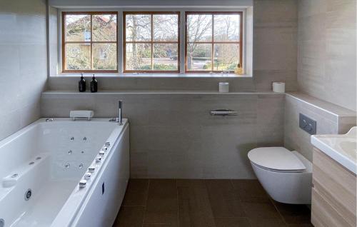 uma casa de banho branca com uma banheira e um WC em 4 Bedroom Cozy Home In Jnkping em Jönköping