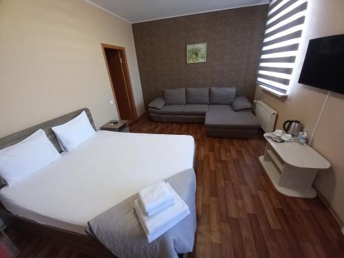 een slaapkamer met een groot wit bed en een bank bij Prometey Hotel in Dniprodzerzhynsʼk