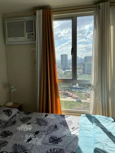 a bedroom with a bed and a large window at Studio near Ayala Vertis North in Manila