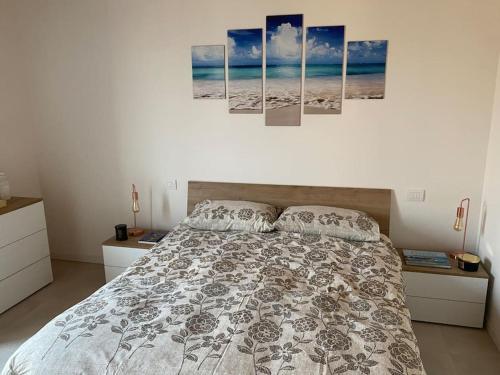 a bedroom with a bed with four paintings on the wall at Appartamento in Valpolicella (AquardensGardaVerona in Settimo