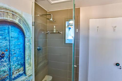 a bathroom with a shower with a blue door at 10 AKROTIRI, SANTORINI ESTATE - Families only in Ballito