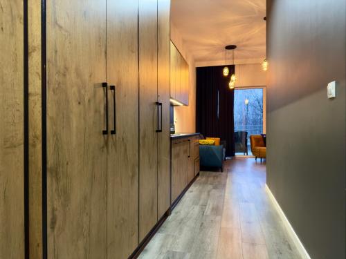a hallway with wooden cabinets and a living room at Apartament Szafirowy in Zarzecze