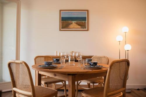 - une table en bois avec des chaises et des verres à vin dans l'établissement Appartement La Case, à Soorts-Hossegor