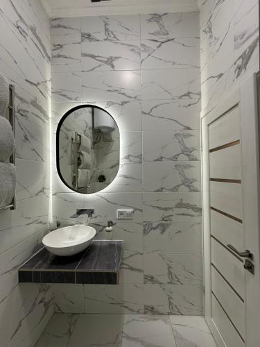 a white bathroom with a sink and a mirror at Квартира на Огієнка 15 in Lviv