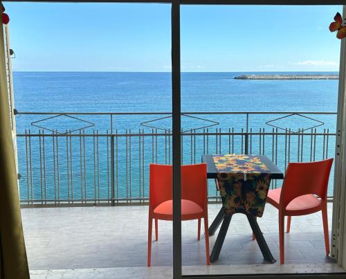 Una mesa y sillas en un balcón con vista al mar. en LA MANSARDA, en Giardini Naxos