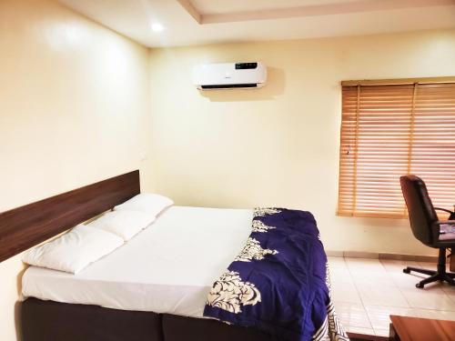 a bedroom with a bed and a chair in a room at Central District Apartment (Abuja) in Aso