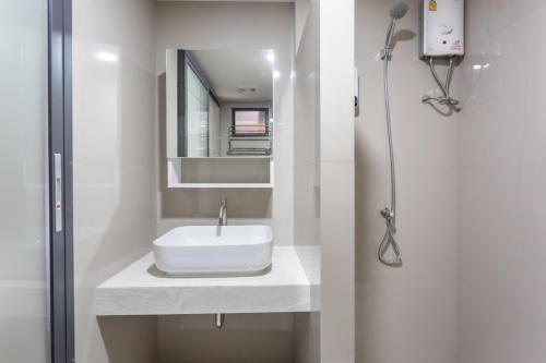 Baño blanco con lavabo y espejo en โรงแรมเซเว่นรัชดา S7VEN RATCHADA, en Ban Na Song